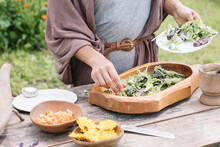Anonymous Hand Making Fresh Salad With Wildflowers