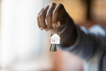 Welcome to new house. Close up of young african american man hand hold bunch of keys. Cropped shot of black guy real estate agent realtor give offer you client key from home flat apartment. Copy space