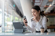 © amnaj - Young Asian businesswoman enjoy shopping online using credit card at a coffee shop.