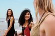 © Milles Studio/Stocksy - Cheerful ethnic woman with beer walking near sea with friends