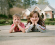 © Jakob Lagerstedt/Stocksy - A young boy and his sister laying on a driveway