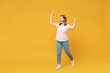 Full length of young caucasian overjoyed excited woman 20s wearing basic pastel pink t-shirt, jeans do winner gesture clench fist celebrating isolated on yellow color background studio portrait.