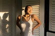 © Felix Hug/Stocksy - young asian woman in white tank top stretching in the morning sun on her balcony.