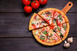 © Jenifoto - Healthy, gluten free cauliflower crust pizza with tomatoes, mushrooms and spinach. Top down view with cut slices. Table scene on a dark wood background.
