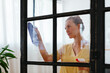 © BONNINSTUDIO/Stocksy - Young woman cleaning window at home