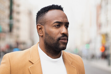 Handsome afro-american man biting his lip and looking aside in Gran via, Madrid.