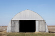 Corrugated Metal Farm Building in a Field under a Blue Sky