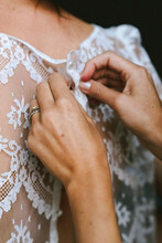 Buttoning Up The Bride In Her Wedding Dress