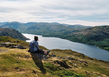 Female And Her Dog Sat On Hallin Fell Above Ullswater. Lake District, Cumbria, UK.