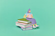 © Yaroslav Danylchenko/Stocksy - Stack of books with reading papercraft girl.