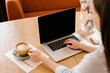 © Alina Hvostikova/Stocksy - Young woman drinking coffee while working with laptop