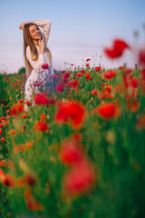 Wall Mural - beautiful red poppies in the foreground. girl posing in white dr