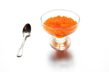 Wall Mural - Delicious red caviar in a transparent glass and a silver spoon isolated on a white background