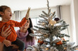 © Milles Studio/Stocksy - Mother and daughter decorating Christmas tree together