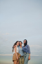 Mom And Daughters Looking At Camera On Hilltop At Sunset.
