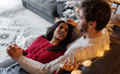 © Milles Studio/Stocksy - Ethnic woman speaking with boyfriend on sofa on Christmas eve