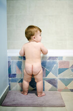 Naked baby standing in bathroom