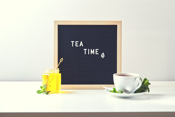 Wall Mural - Tea time. Black letter board with text on table with glass cup of tea with mint leaves