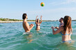 © Ivan Gener/Stocksy - Friends tossing a ball around in the ocean