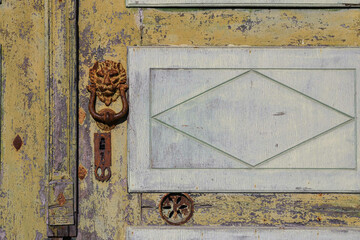 Wall Mural - Close-up of an old, weathered door with a rusty knocker in the shape of a lion's head, Italy