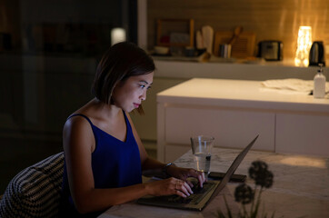 Woman working from home at night - looking at illuminated screen