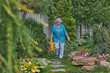 © Dmitry Borovikov/Stocksy - Beautiful elderly woman caring for plants in her garden