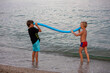 © Nataliia Makarovska - cute tanned children explore a banana by the sea on the beach on a summer evening, horizontally