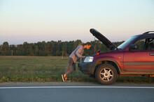 Woman Examining Engine Of Broken Car In Countryside