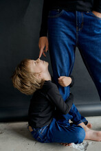Mother And Son In The Studio On A Black Paper Background In Jeans And A Black Long Sleeve Jacket