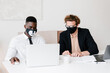 © Alina Hvostikova/Stocksy - Diverse coworkers in masks browsing data on laptop together