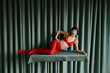 © ulas & merve/Stocksy - woman with red outfit in front of green curtain