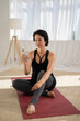 © Sibstock/Stocksy - woman using phone after yoga class