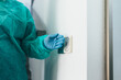 © MyMicrostock/Stocksy - Surgeon using a contactless switch to open a door