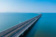 © YiChao Ma/Stocksy - Aerial view of bridge road with cars over lake or sea