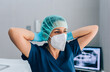 © MyMicrostock/Stocksy - Dental surgeon woman wearing mask and cap while looking away wit