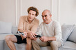 © Alina Hvostikova/Stocksy - Young man teaching senior father to play video game