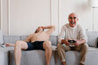 © Alina Hvostikova/Stocksy - Cheerful senior father and son playing video game