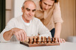 © Alina Hvostikova/Stocksy - Happy senior man with son playing chess at home