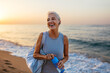 © BONNINSTUDIO/Stocksy - Happy female athlete with bottle of water near sea