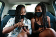 © Jimena Roquero/Stocksy - Two young women checking their smart phones inside a car