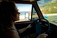 Young Woman Driving A Vintage Camper Van Though The Californian Coast.