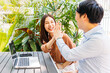 © twinsterphoto - Cheerful and excited young Asian man and woman celebrating good news and success by giving high five to each other while sitting in modern cafe