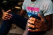 © Erin Brant/Stocksy - Torso of black male wearing VALID t-shirt sitting on ground grasping knees