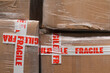© Jelena Jojic Tomic/Stocksy - A stock photo close up of cardboard packages wrapped in the protective foil and fragile adhesive warning tape