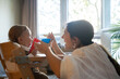 © Luis Velasco/Stocksy - Young Mother Feeding To Her Baby On A Highchair At Home.