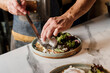 © Guaita Studio/Stocksy - Hands of cook placing poached eggs on top of avocado toast in a nice plate in kitchen restaurant