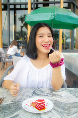 Asian teenager with pink braces on teeth eating red velvet cake