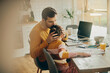 © Drazen - Caring father kissing his daughter while working at home.