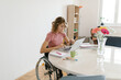 © Mihajlo Ckovric/Stocksy - Young woman in a wheelchair working from home on her laptop