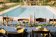© Adrian Cotiga/Stocksy - Table with linen tablecloth and bouquets located near pool during wedding